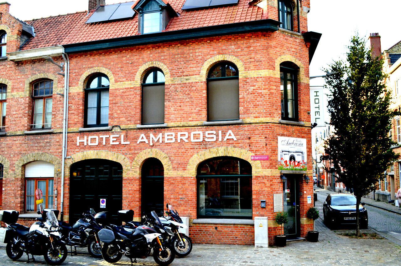Un edificio de ladrillo con el letrero "HOTEL AMBROSIA" y varias motocicletas estacionadas frente a él.