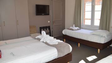 A hotel room with two beds, a television, a door, and a window with curtains.