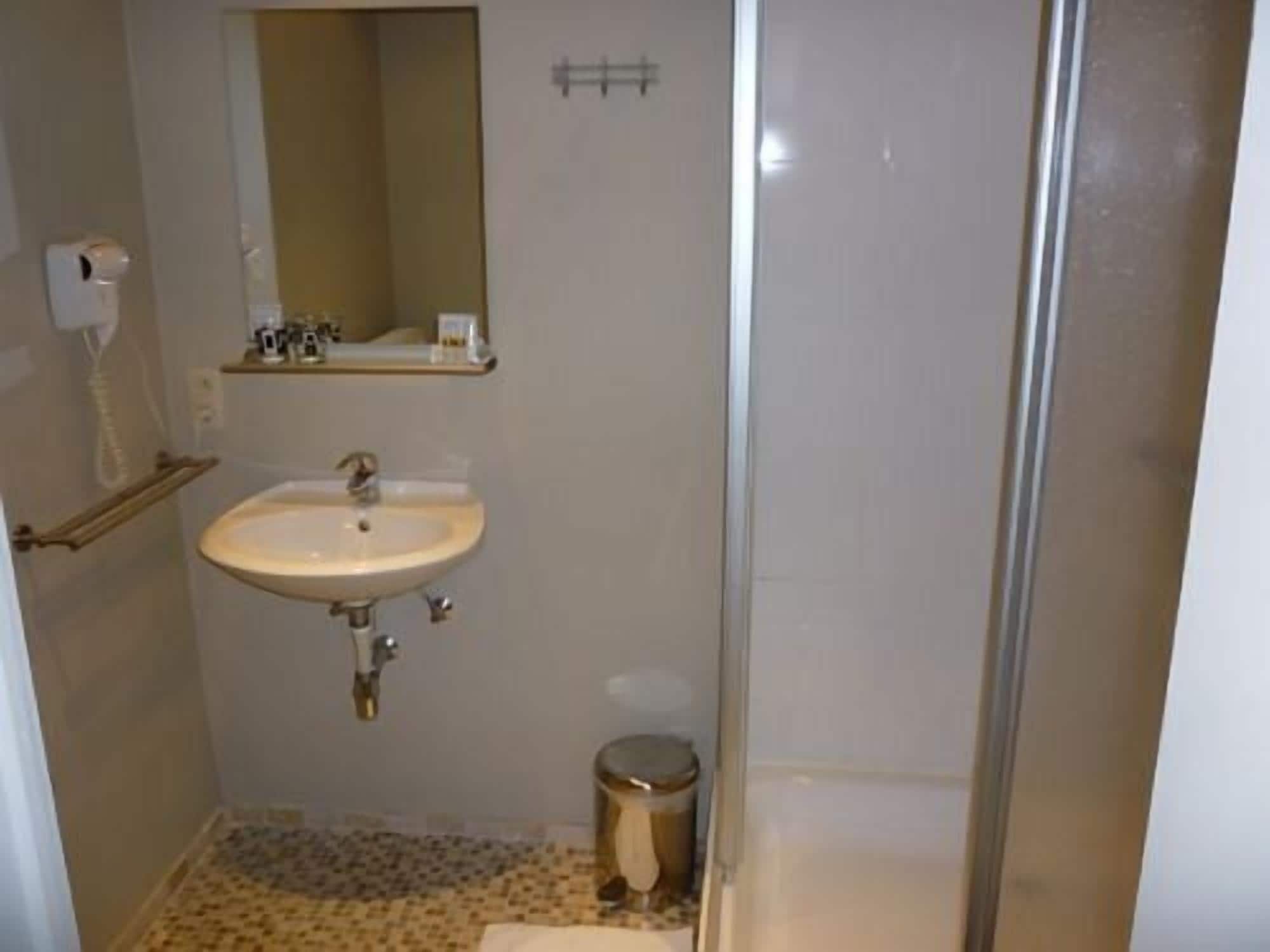 A small bathroom with a sink, mirror, and toilet.