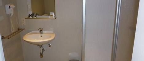 Un baño pequeño con lavamanos, espejo e inodoro.