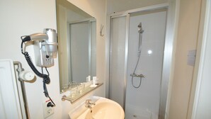 A bathroom with a sink, mirror, hairdryer, and shower. - Hotel Ambrosia (Ypres)