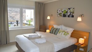 A neatly made bed with white linens, a wooden headboard, and two bedside lamps. - Hotel Ambrosia (Ypres)