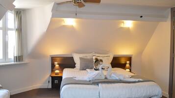 A bedroom with a bed, a nightstand, a lamp, a ceiling fan, and a window with curtains.