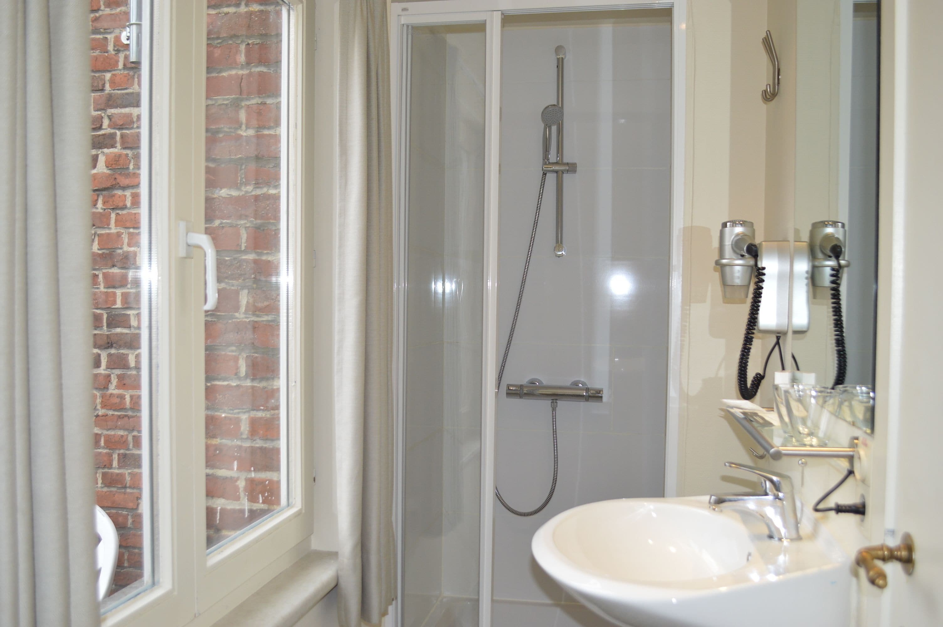 A bathroom with a glass-enclosed shower, a white sink, and a mirror.