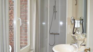 A bathroom with a glass-enclosed shower, a white sink, and a mirror.