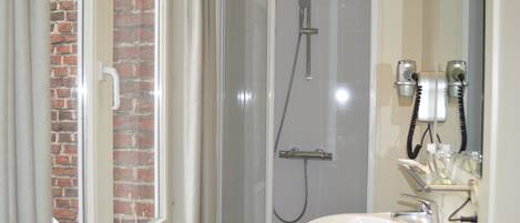Un baño con ducha de vidrio, lavabo blanco y espejo.