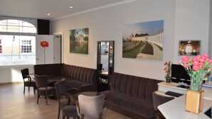 A modern waiting area with a sofa, chairs, a small table, and a refrigerator. - Hotel Ambrosia (Ypres)