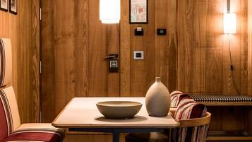 Un interno in legno con un tavolo, una ciotola e un vaso. C'è una panca con un cuscino a righe.