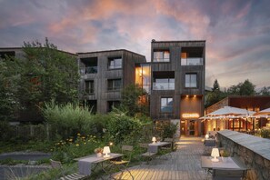 A modern hotel with a courtyard, outdoor seating, and a wooden facade. - Eden Hotel (Bormio)