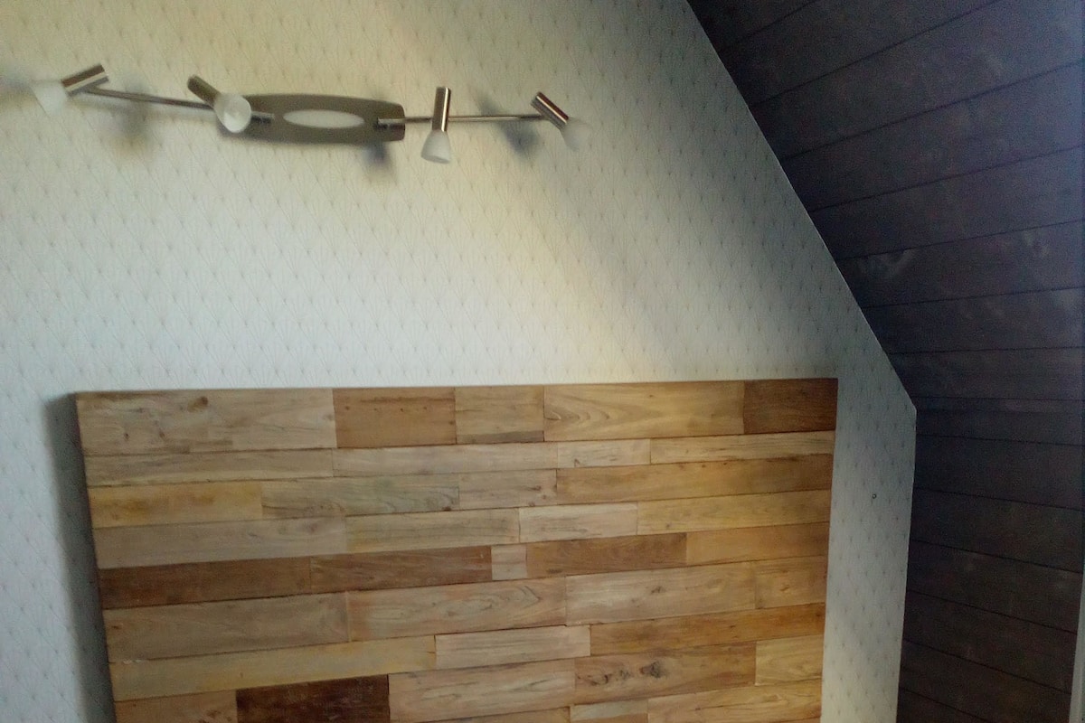 A bedroom with a wooden headboard, a white bedspread, and a nightstand.