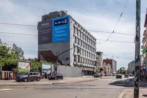 Un edificio con un cartel grande que anuncia 'ARASS HOTEL' y 'Badkammers Keukens Verwarming'.
