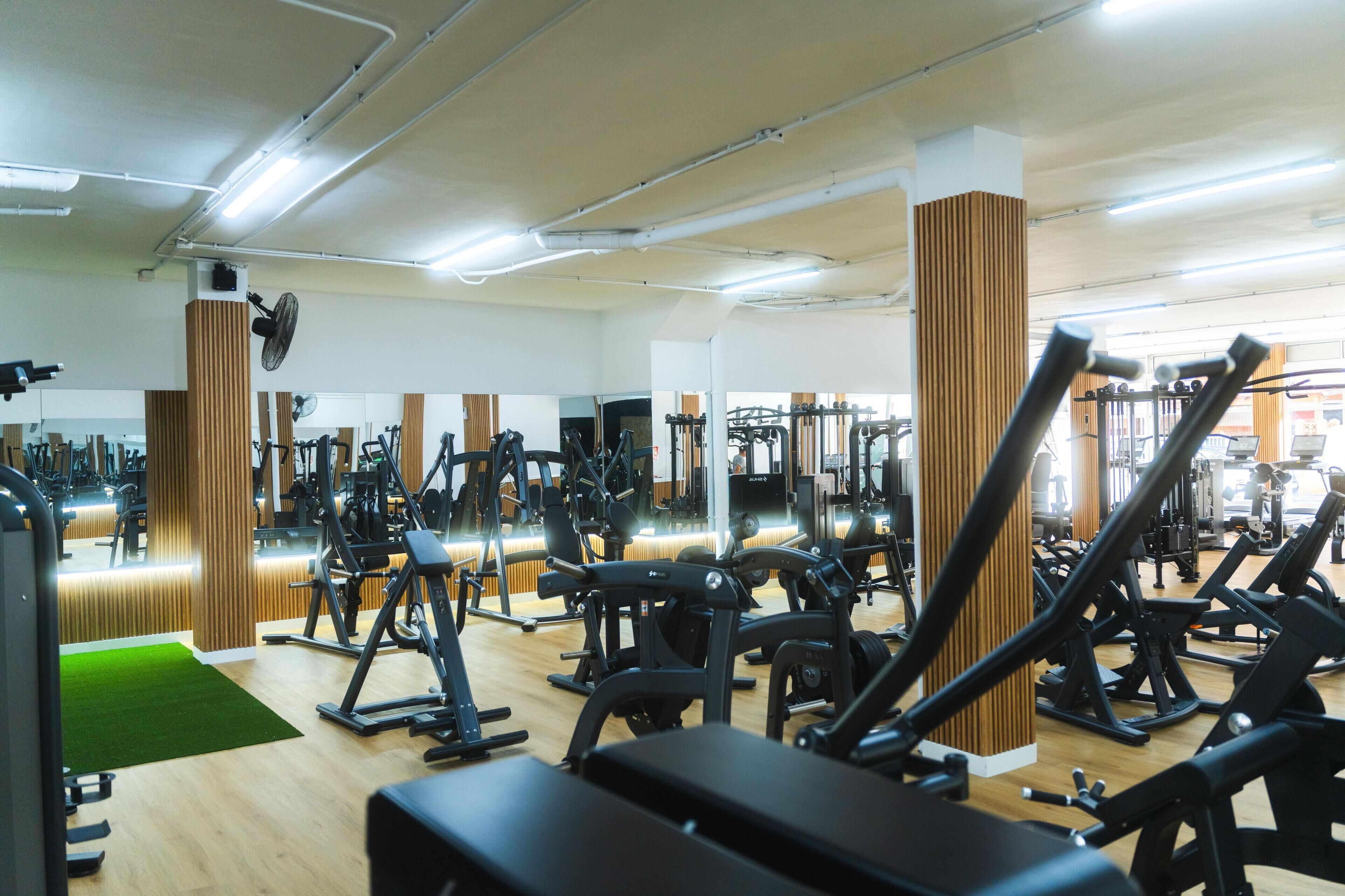A gym with various exercise equipment, wooden accents, and a green mat.