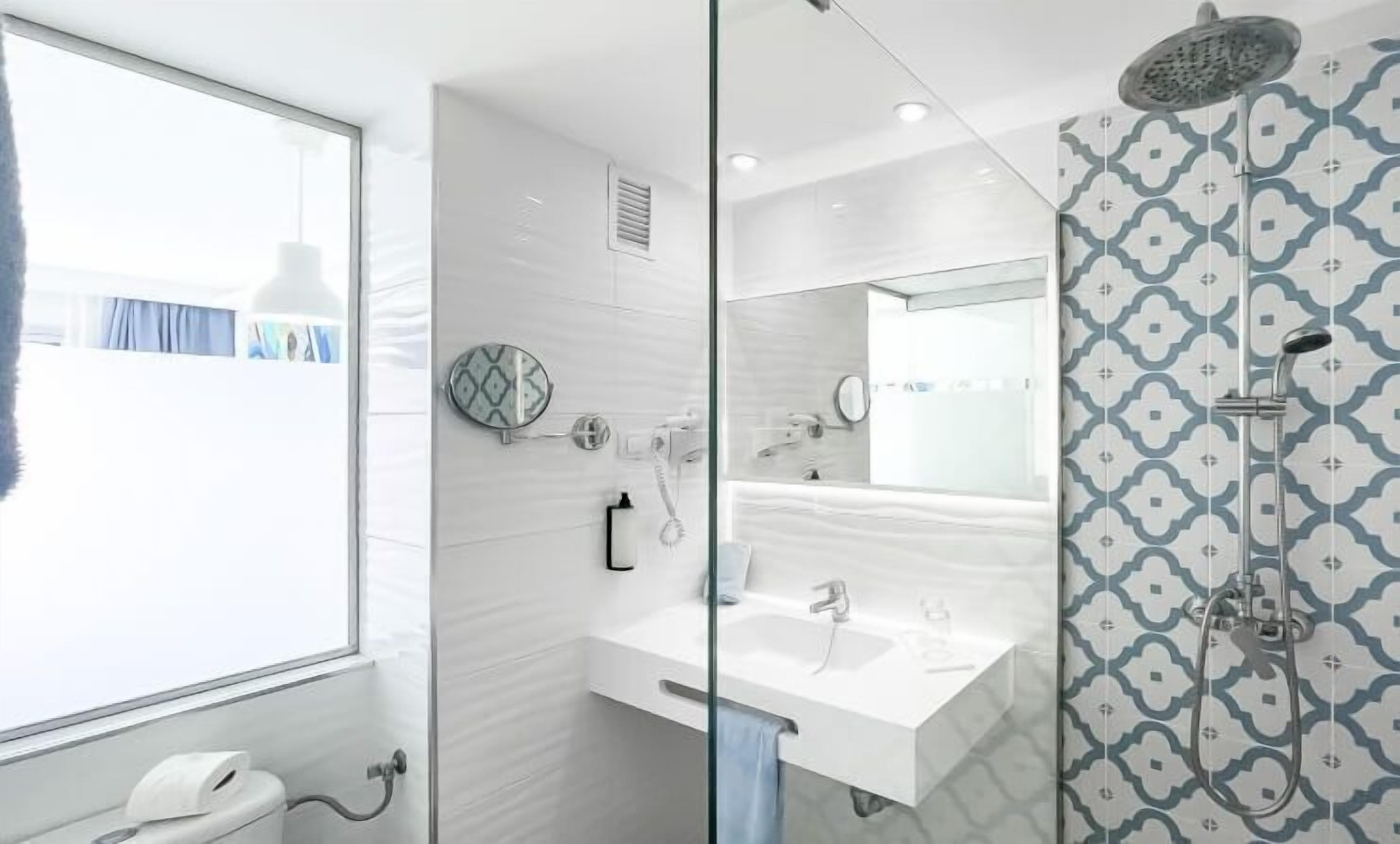 A modern bathroom with a glass shower enclosure, a white sink, and a mirror.