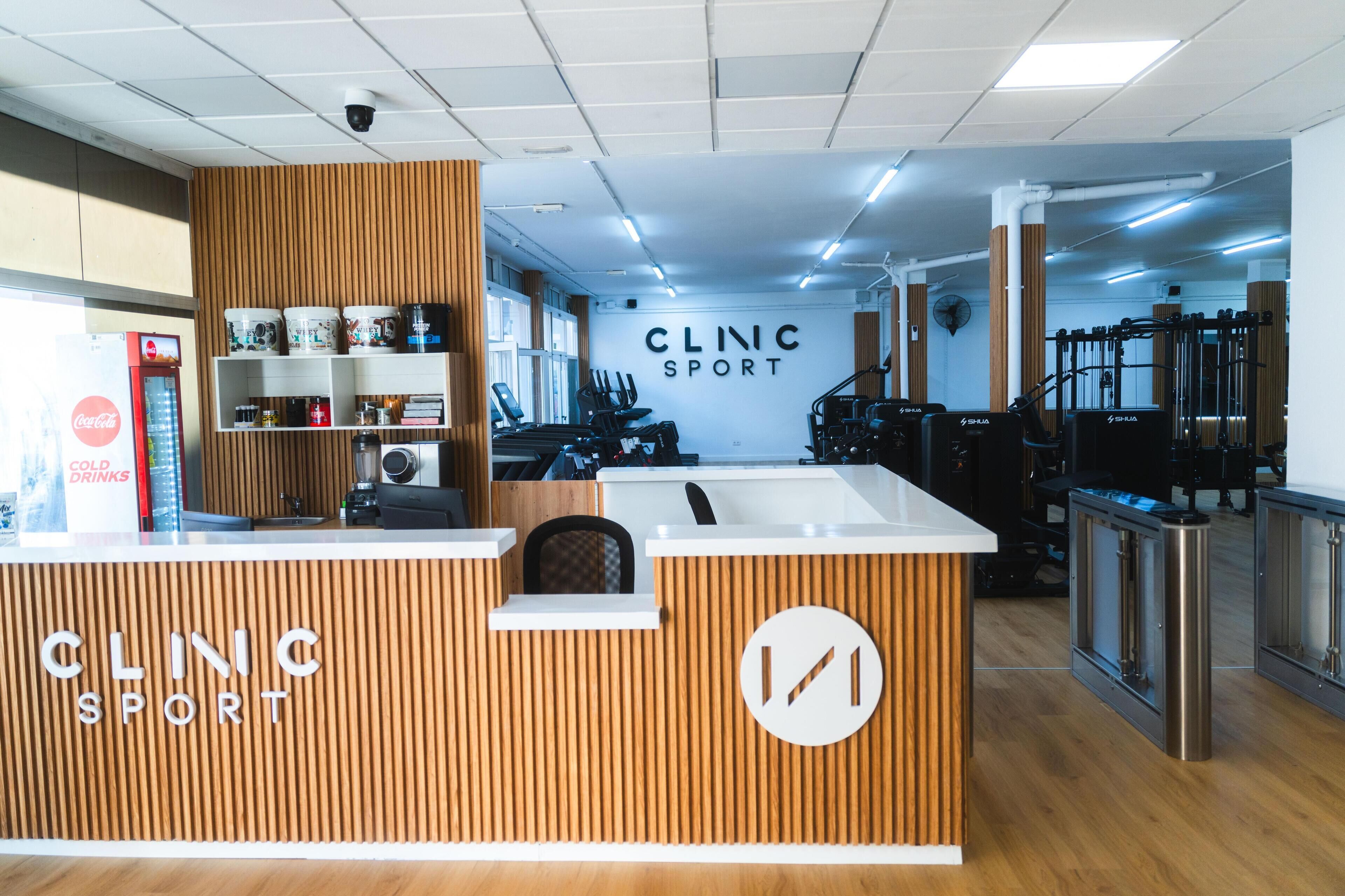 Een receptiebalie met een houten paneel en een bordje met de tekst 'CLINIC SPORT'.