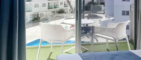 Une chambre d’hôtel dotée d’une grande fenêtre, d’un lit et d’un balcon avec des meubles pour se détendre à l’extérieur.
