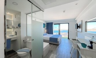 A modern hotel room with a balcony, a separate bathroom, a bed, and a desk area.