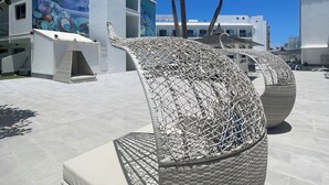 Outdoor seating with woven chairs and a mural on the building. - Corralejo Surfing Colors Hotel&Apartments (La Oliva)
