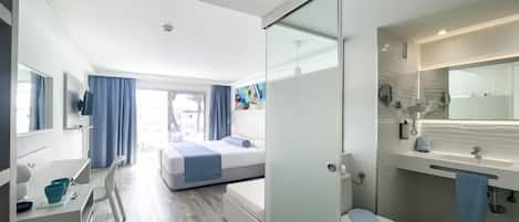 A modern hotel room with a bed, a bathroom, and a desk with a chair.