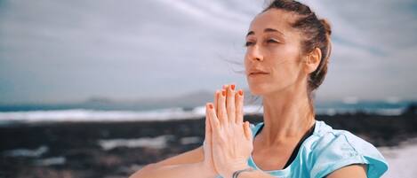 A person in a light blue shirt with a number on the back, standing with hands in a prayer position.
