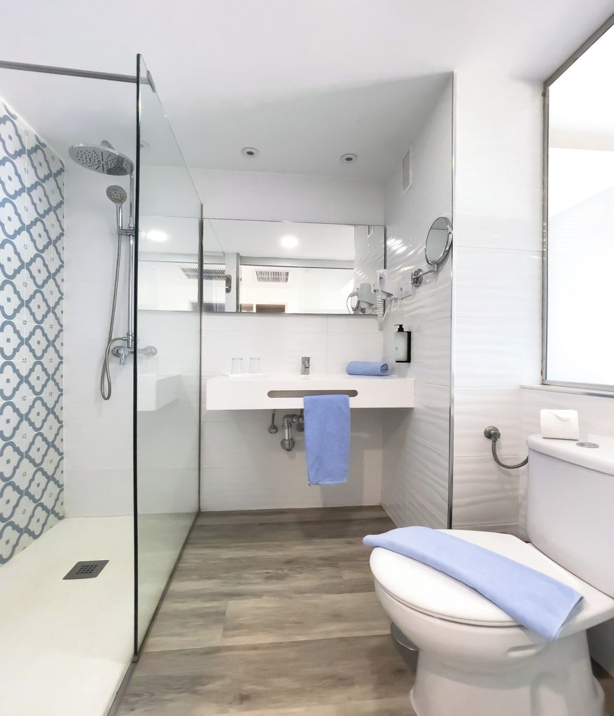 A modern bathroom with a glass shower enclosure, a white toilet, and a sink with a mirror above it.