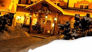 Ein Hotel mit traditioneller Holzfassade, einem zentralen Eingang mit Doppeltüren und einem Schild darüber.