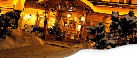 A hotel with a traditional wooden facade, a central entrance with double doors, and a sign above the doors.