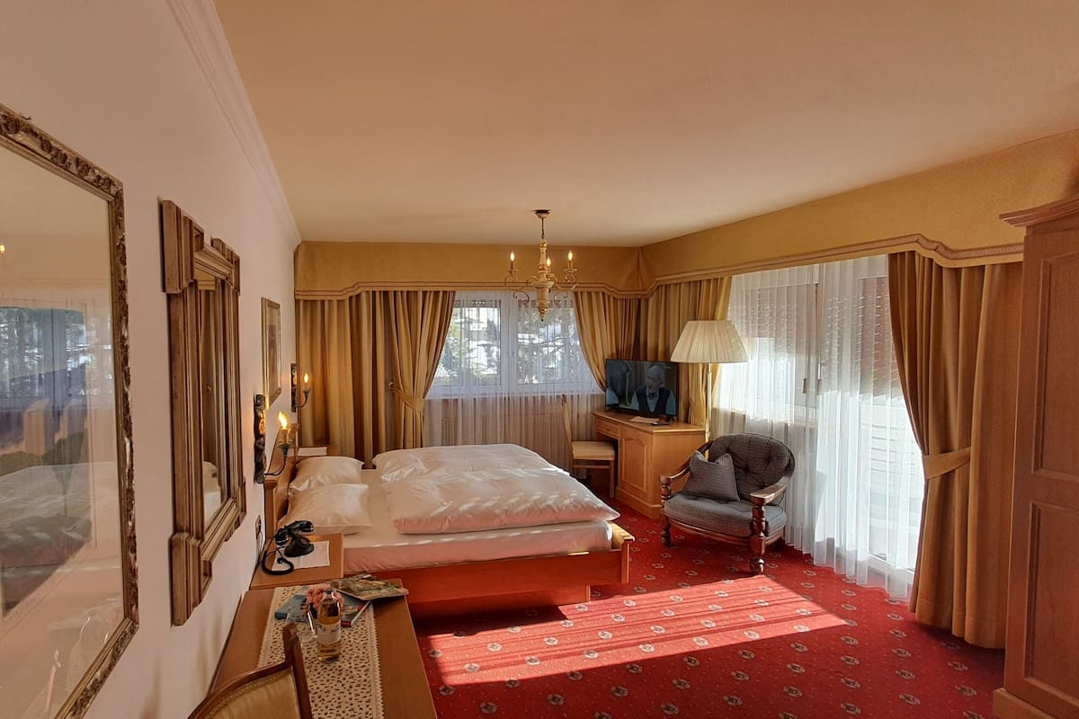 Ein Hotelzimmer mit einem großen Bett, einem Schreibtisch mit Lampe, einem Sessel und einem Kleiderschrank.