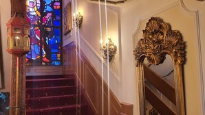 Eine prächtige Treppe mit aufwendiger Geländerarbeit, einem Buntglasfenster und einem dekorativen Spiegel.