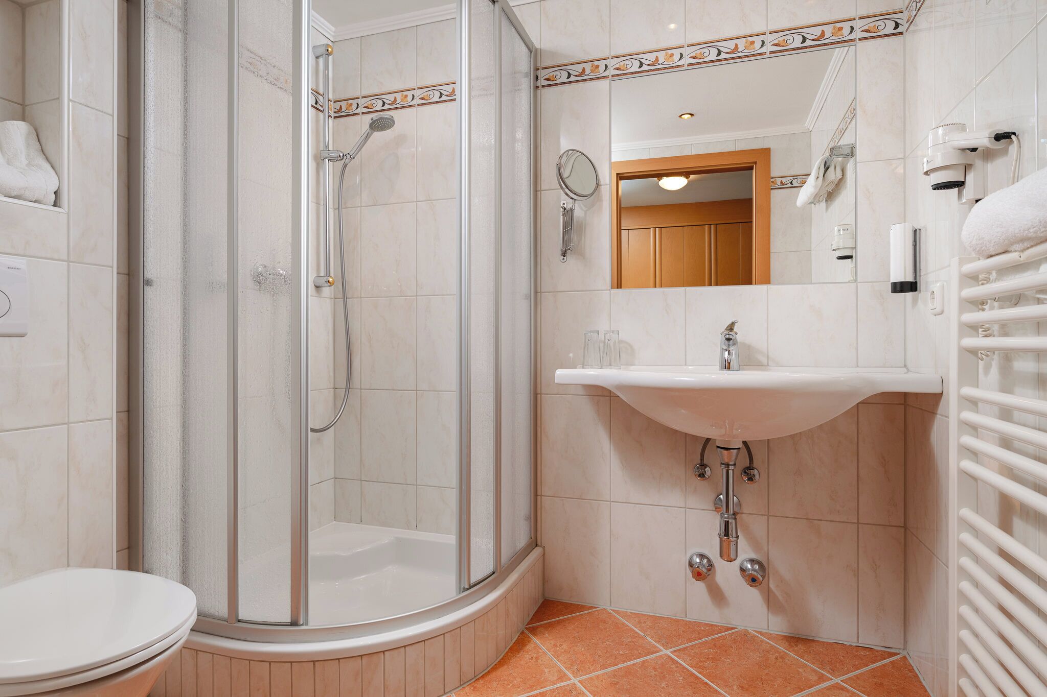 Une salle de bain avec une douche à parois de verre, un lavabo avec un miroir et un porte-serviettes.