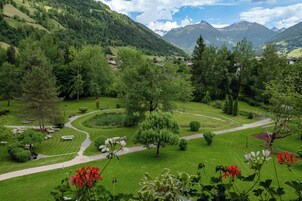 A lush green landscape with a winding path, trees, and a view of distant mountains.