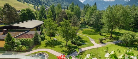 Un paisaje montañoso con un puente, senderos y un edificio de techo inclinado.