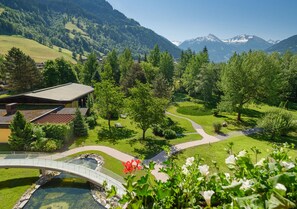 Un paisaje montañoso con un puente, senderos y un edificio de techo inclinado.