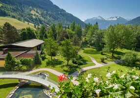 A mountain landscape with a bridge, pathways, and a building with a sloped roof.