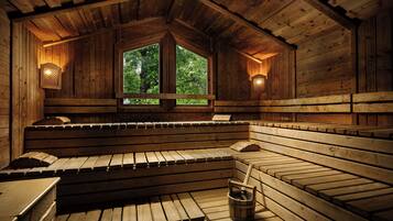 Una sauna de madera con bancos y una ventana, y un balde en el suelo.
