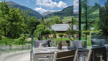 A dining area with a table set for two, overlooking a mountainous landscape.