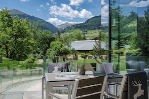 A dining area with a table set for two, overlooking a mountainous landscape.