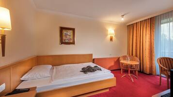 Une chambre d’hôtel avec un lit, une chaise, une table, une lampe, un tableau et une vue sur l’extérieur.