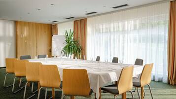 A conference room with a round table, chairs, a whiteboard, and a potted plant.