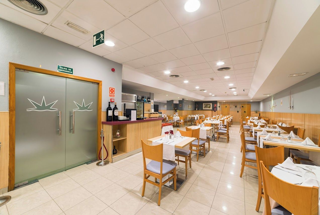A restaurant with multiple tables and chairs, a counter with a menu, and an emergency exit door.