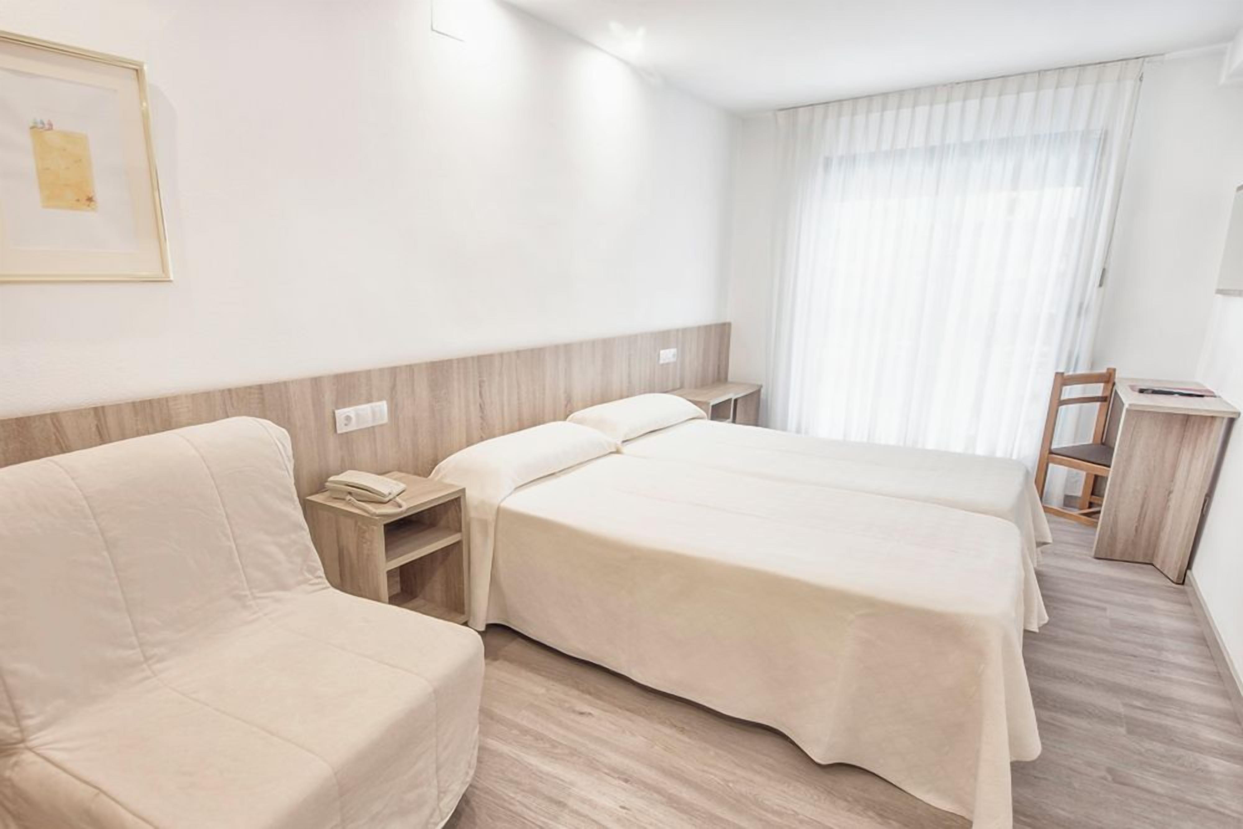 Una habitación de hotel con dos camas, un sofá, un escritorio y una silla.