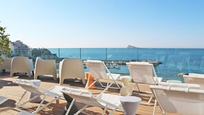 A deck with white lounge chairs facing a marina and the sea. - Hotel Montemar Benidorm (Benidorm)