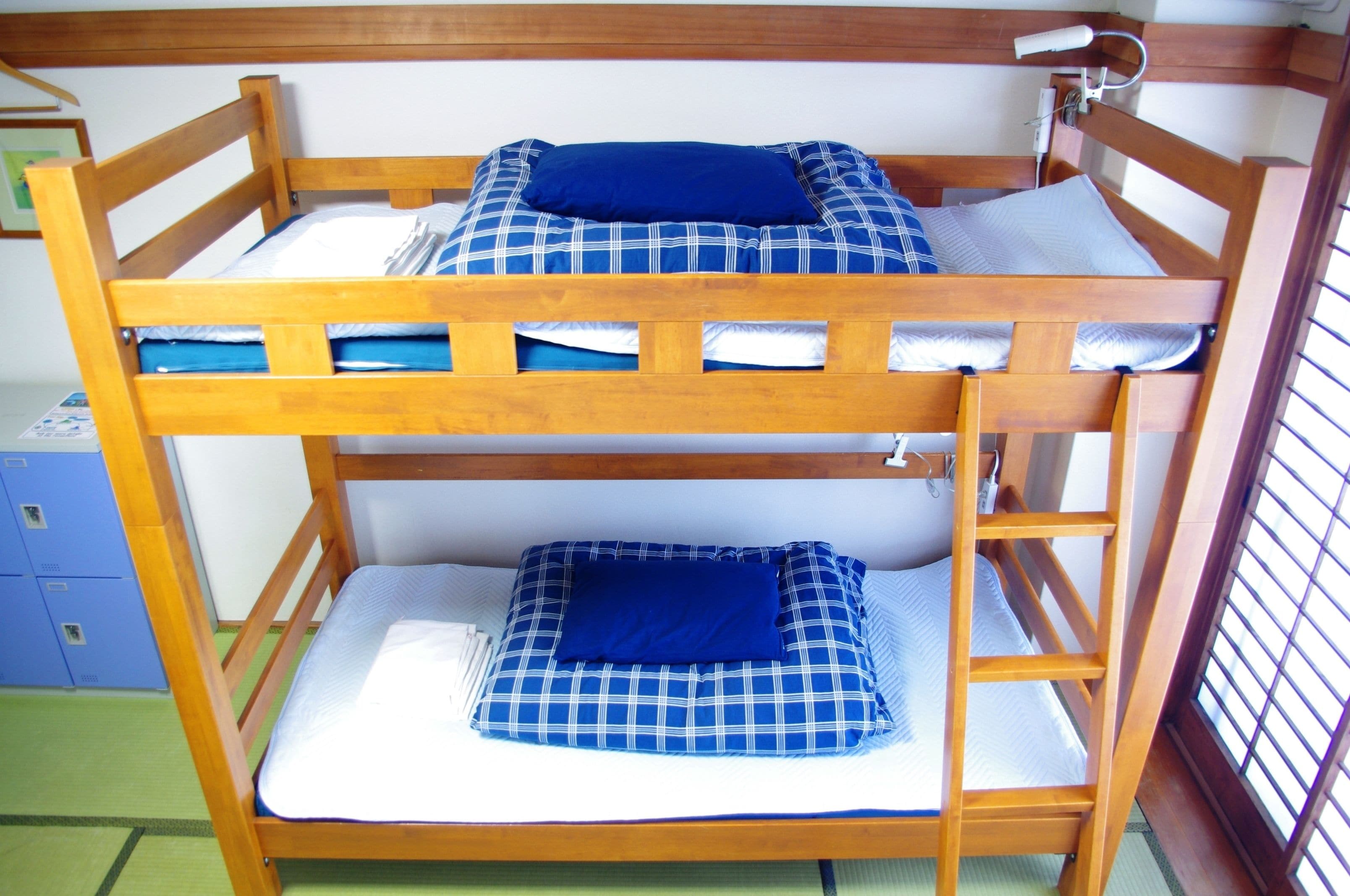 A bunk bed with two levels, each with a mattress and a blue pillow.