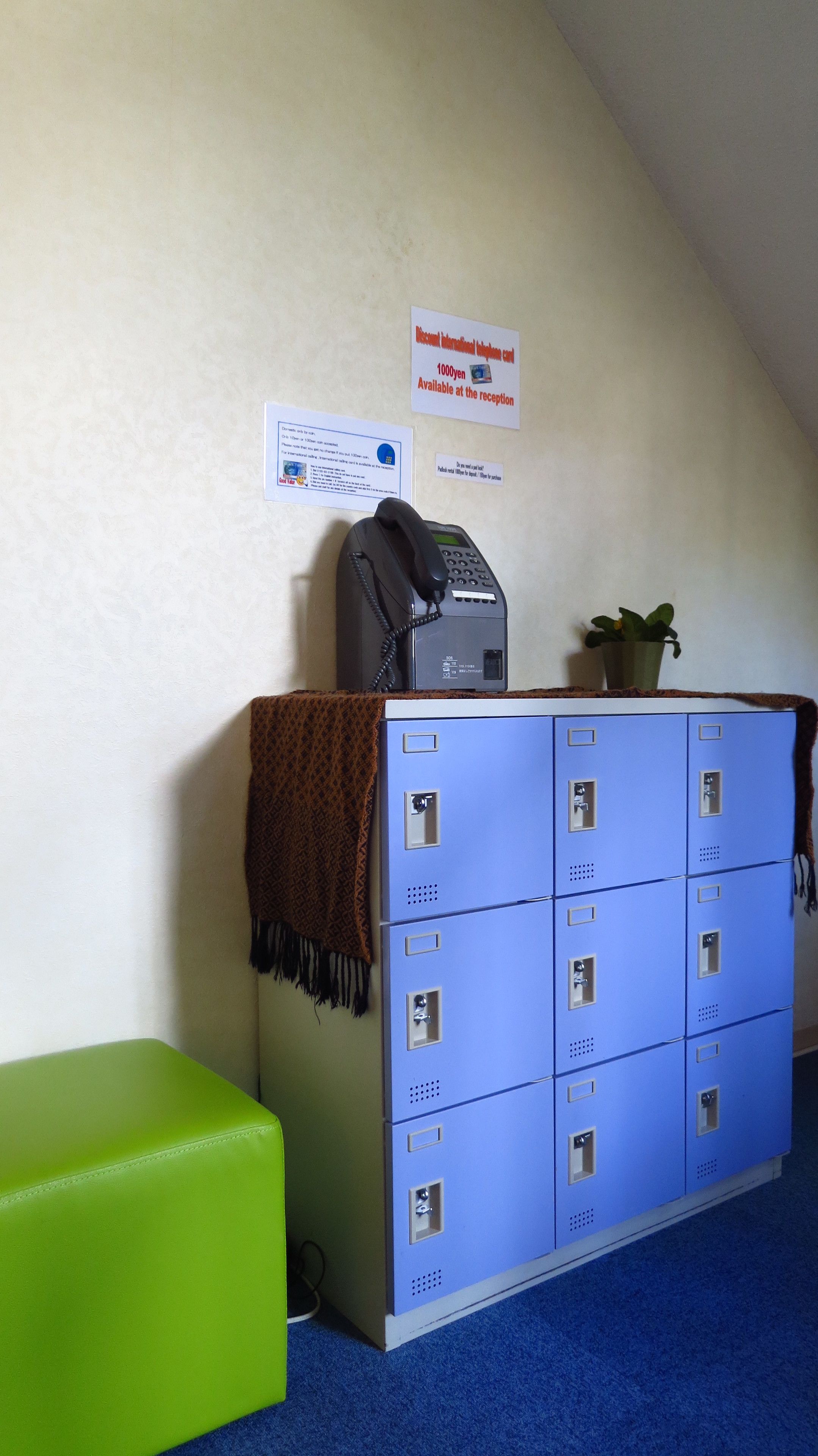A reception area with a phone, a sign offering a 1000 yen discount, and blue lockers.