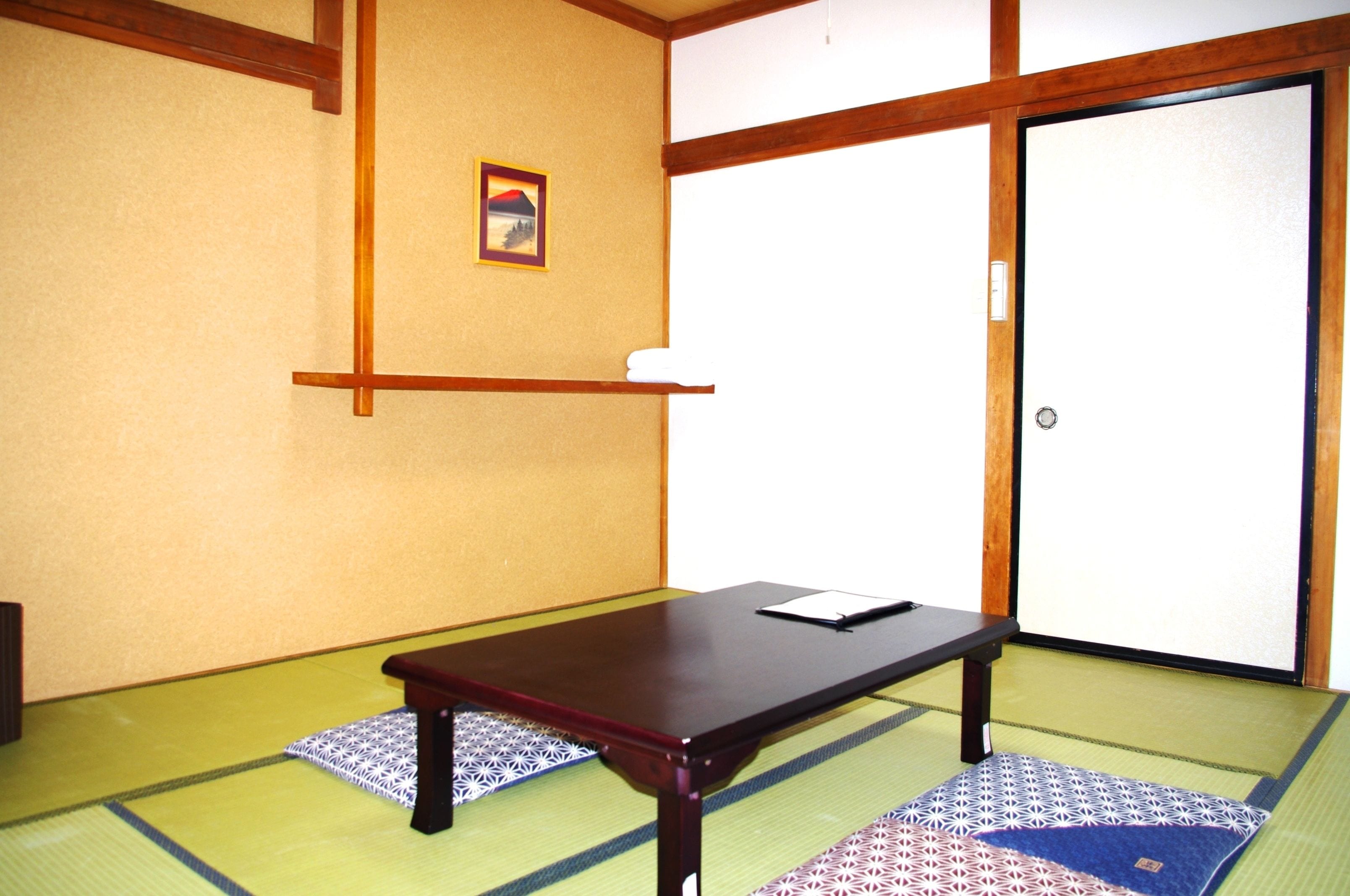 Um quarto japonês tradicional com tatames, uma mesa de madeira baixa e um portas correderas.