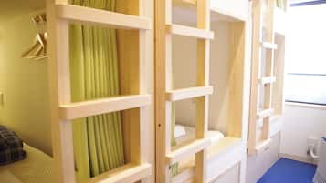 A room with bunk beds, a blue carpet, and a green curtain.