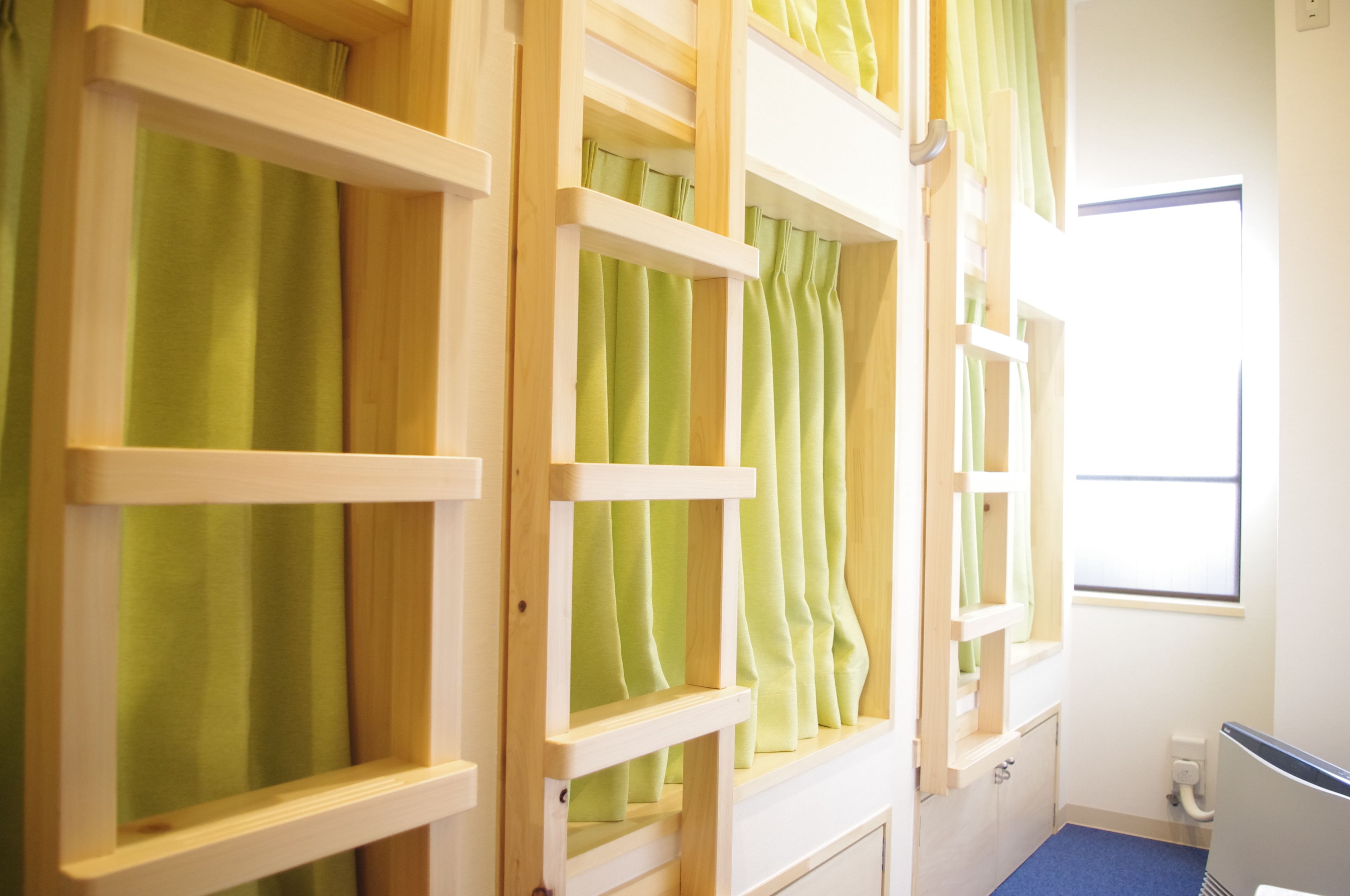 Una habitación con literas, cortinas verdes y una ventana con persianas.