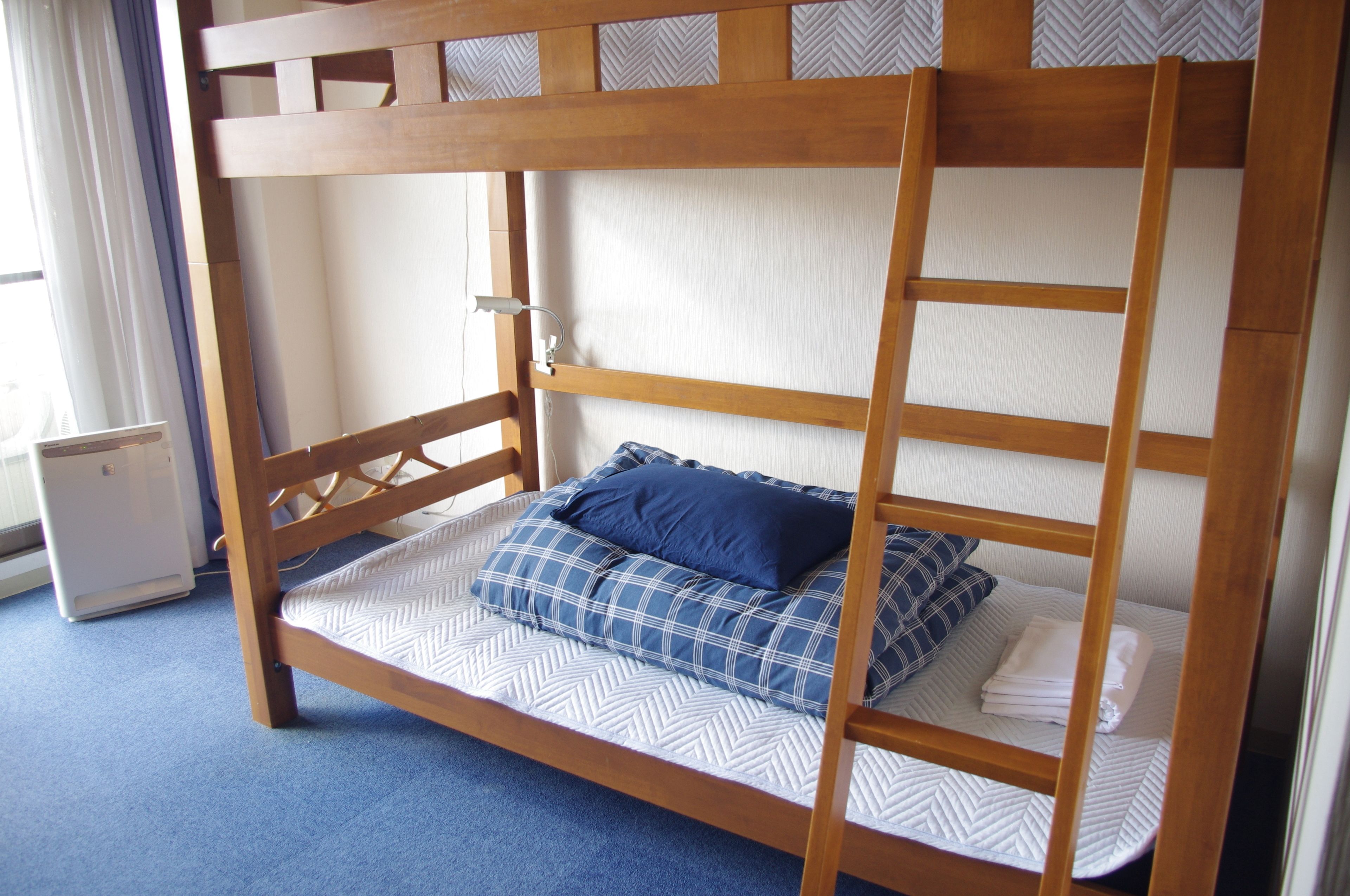 A bunk bed with a wooden frame and white bedding.