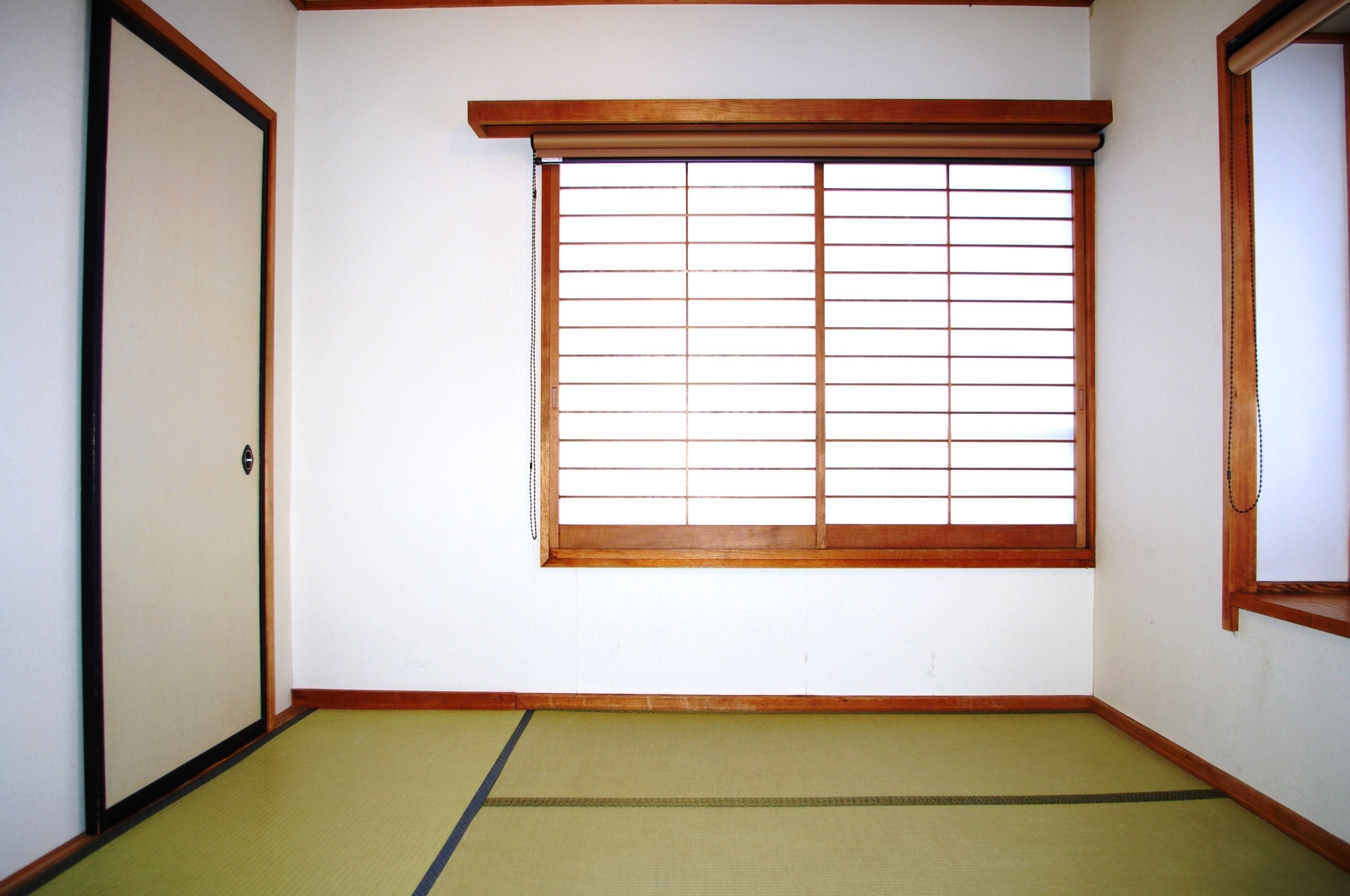 A traditional Japanese room with tatami flooring, a shoji screen window, and a sliding door.