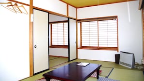 Une pièce de style japonais traditionnel, avec un sol recouvert de tatamis, des portes coulissantes et une table faite de tatamis.
