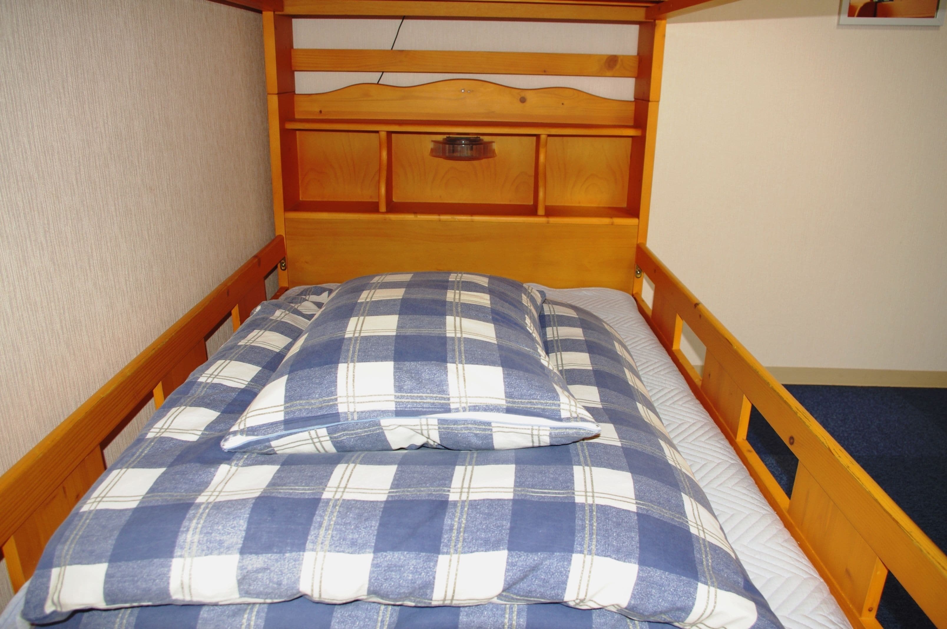 A single bed with a wooden headboard and a plaid bedspread.